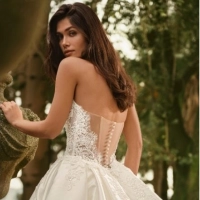 Bride trying on a lace wedding gown with help from a bridal stylist inside an elegant Enzoani boutique during her first bridal appointment.