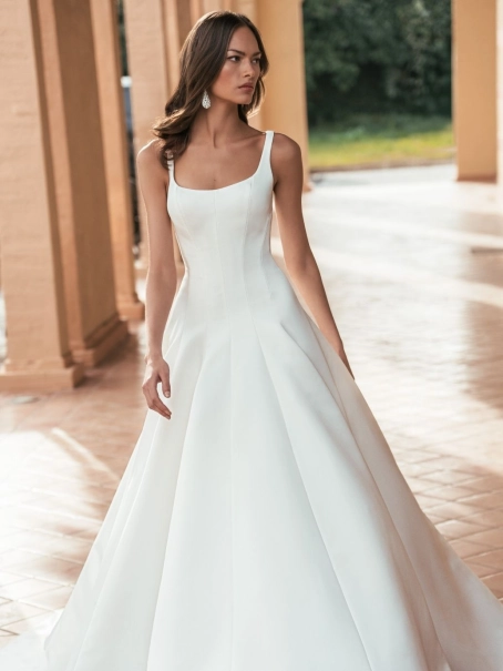 Blue by Enzoani Ulandra is a luxury satin ballgown wedding dress featuring a clean structured bodice, elegant scoop neckline, wide shoulder straps and a sweeping cathedral-length train. Designed for modern brides seeking a minimalist designer wedding gown