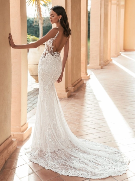 Blue by Enzoani Ularia is a luxury fitted mermaid wedding dress featuring an illusion plunge neckline, delicate shoulder straps, intricate beaded lace embroidery and a figure-enhancing silhouette. Designed for brides seeking a glamorous designer wedding go