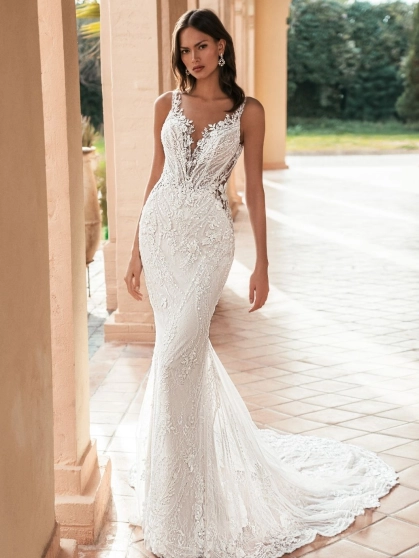 Blue by Enzoani Ularia is a luxury fitted mermaid wedding dress featuring an illusion plunge neckline, delicate shoulder straps, intricate beaded lace embroidery and a figure-enhancing silhouette. Designed for brides seeking a glamorous designer wedding go