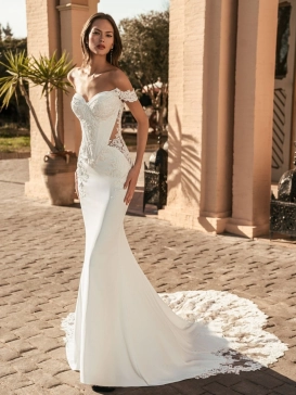Blue by Enzoani Umani is a luxury fitted mermaid wedding dress featuring a romantic off-the-shoulder neckline, sculpted corset-inspired bodice, illusion side detailing and delicate floral lace appliqués. Designed for brides seeking a sophisticated designer