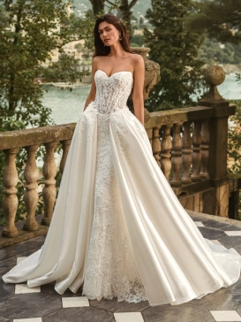 Bride wearing the Enzoani WANDA wedding dress, a romantic strapless lace fit-and-flare bridal gown with an illusion corset bodice and detachable satin overskirt, perfect for luxury, modern, and destination weddings.