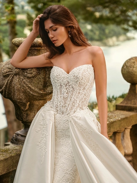 Bride wearing the Enzoani WANDA wedding dress, a romantic strapless lace fit-and-flare bridal gown with an illusion corset bodice and detachable satin overskirt, perfect for luxury, modern, and destination weddings.