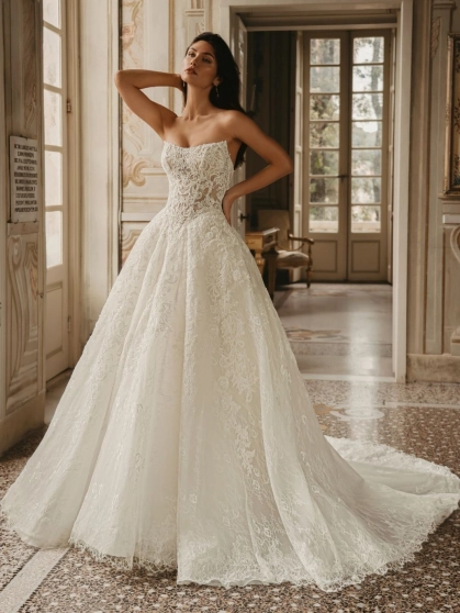 Enzoani West wedding dress. A luxury strapless bridal ball gown featuring an intricately detailed, semi-sheer sculpted corset bodice with sequinned baroque lace and delicate Chantilly lace. The full, dramatic tulle ballgown skirt cascades into a long, roma