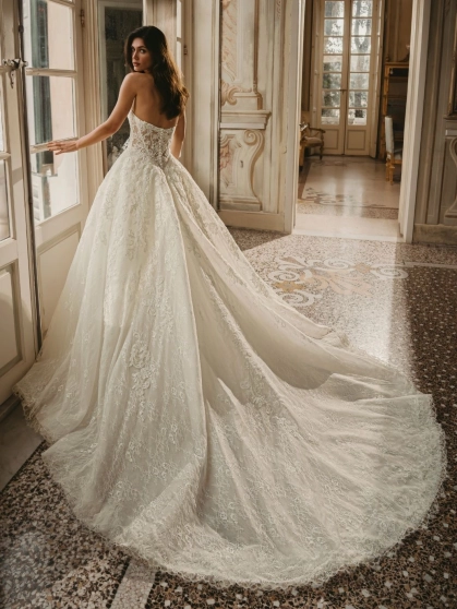 Enzoani West wedding dress. A luxury strapless bridal ball gown featuring an intricately detailed, semi-sheer sculpted corset bodice with sequinned baroque lace and delicate Chantilly lace. The full, dramatic tulle ballgown skirt cascades into a long, roma