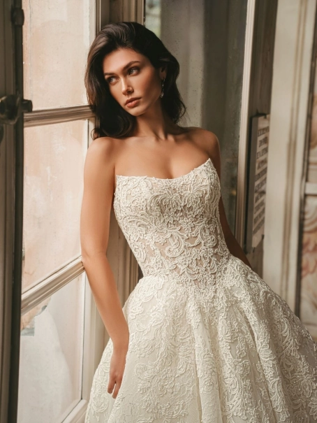 Enzoani West wedding dress. A luxury strapless bridal ball gown featuring an intricately detailed, semi-sheer sculpted corset bodice with sequinned baroque lace and delicate Chantilly lace. The full, dramatic tulle ballgown skirt cascades into a long, roma