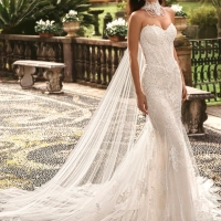 Enzoani luxury wedding dress featuring a romantic mermaid silhouette with intricate floral lace appliqué, fitted sweetheart bodice, illusion detailing and a dramatic cathedral-length tulle train. Designed for modern brides seeking a designer wedding dress