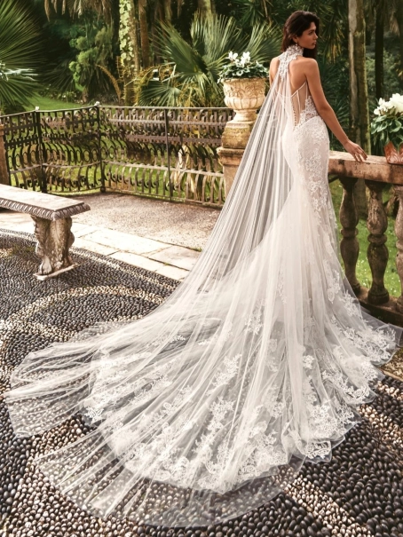 Enzoani luxury wedding dress featuring a romantic mermaid silhouette with intricate floral lace appliqué, fitted sweetheart bodice, illusion detailing and a dramatic cathedral-length tulle train. Designed for modern brides seeking a designer wedding dress