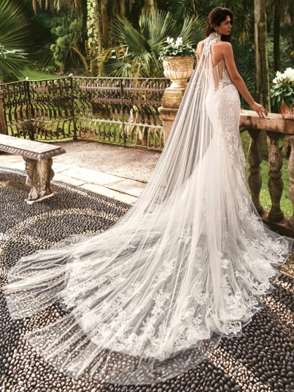 Enzoani luxury wedding dress featuring a romantic mermaid silhouette with intricate floral lace appliqué, fitted sweetheart bodice, illusion detailing and a dramatic cathedral-length tulle train. Designed for modern brides seeking a designer wedding dress