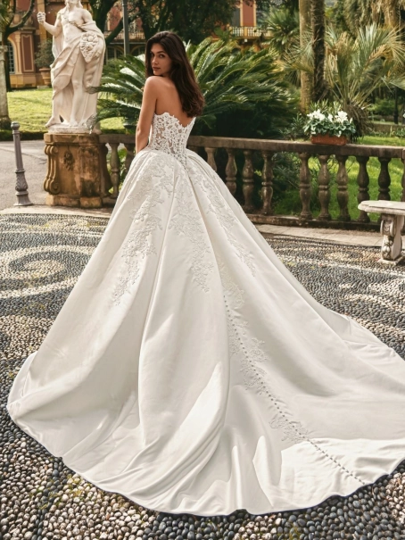 Enzoani Windsor is a luxury ballgown wedding dress featuring an intricately embroidered corset-inspired bodice, romantic sweetheart neckline, elegant satin skirt and ornate lace appliqué detailing. Designed for brides seeking a princess wedding dress with