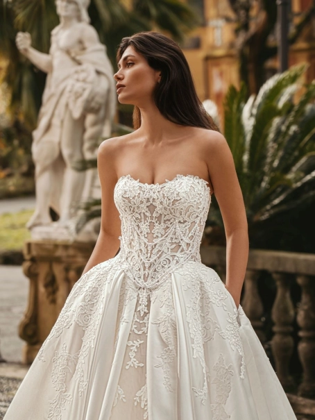 Enzoani Windsor is a luxury ballgown wedding dress featuring an intricately embroidered corset-inspired bodice, romantic sweetheart neckline, elegant satin skirt and ornate lace appliqué detailing. Designed for brides seeking a princess wedding dress with