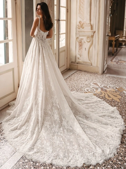 Enzoani Winslow is a luxury A-line wedding dress featuring intricate floral lace embroidery, a softly structured bodice, elegant shoulder straps and a graceful cathedral-length train. Designed for brides seeking a timeless designer wedding gown that blends