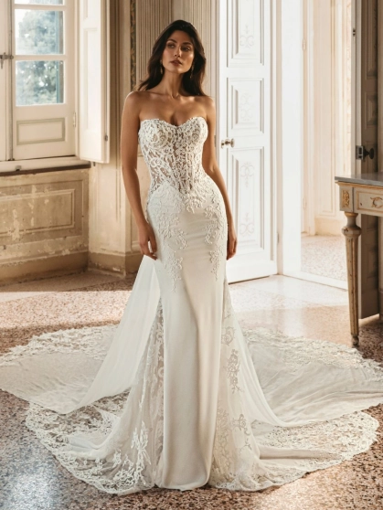 Enzoani Winter is a luxury fitted wedding dress featuring an intricately embroidered illusion corset bodice, sculpted sweetheart neckline, elegant crepe skirt and dramatic detachable lace train. Designed for brides seeking a sophisticated designer wedding