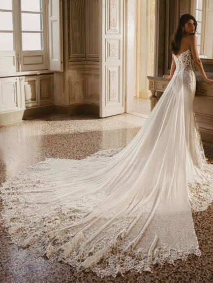 Enzoani Winter is a luxury fitted wedding dress featuring an intricately embroidered illusion corset bodice, sculpted sweetheart neckline, elegant crepe skirt and dramatic detachable lace train. Designed for brides seeking a sophisticated designer wedding
