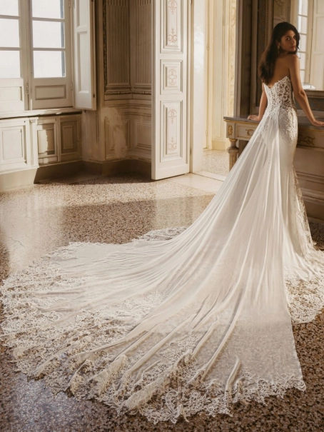 Enzoani Winter is a luxury fitted wedding dress featuring an intricately embroidered illusion corset bodice, sculpted sweetheart neckline, elegant crepe skirt and dramatic detachable lace train. Designed for brides seeking a sophisticated designer wedding