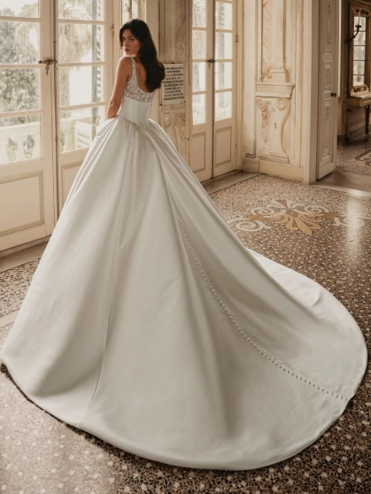 Enzoani Wren is a luxury satin ballgown wedding dress featuring a delicately embroidered lace bodice, elegant square neckline, supportive shoulder straps and a dramatic cathedral-length train. Designed for brides seeking a timeless designer wedding gown th