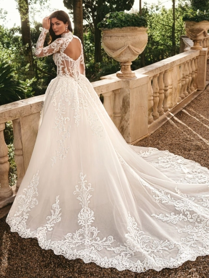 Enzoani Wynn is a luxury princess ballgown wedding dress featuring a high illusion neckline, long lace sleeves, structured corset bodice and intricate embroidered lace detailing throughout. Designed for brides seeking a regal designer wedding gown with cou