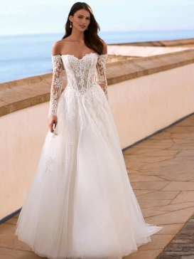 Love Faiza is a romantic A-line wedding dress from the 2027 collection featuring an illusion lace corset bodice, detachable off-the-shoulder long lace sleeves and a flowing soft tulle skirt with floral lace appliqués. Designed by Enzoani for brides seeking