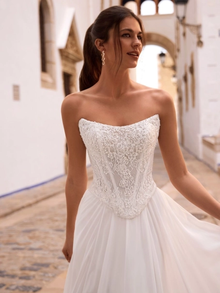 Love by Enzoani FENORA-A is a versatile two-piece designer wedding dress featuring an intricately embellished lace corset bodice paired with a lightweight chiffon A-line skirt. Combining modern bridal fashion with timeless romance, this luxury wedding gown