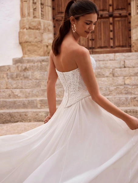 Love by Enzoani FENORA-A is a versatile two-piece designer wedding dress featuring an intricately embellished lace corset bodice paired with a lightweight chiffon A-line skirt. Combining modern bridal fashion with timeless romance, this luxury wedding gown