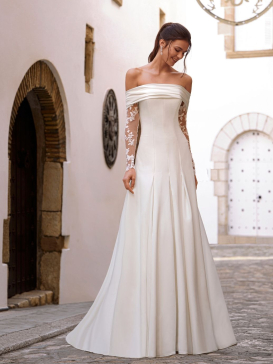 Love by Enzoani FLORENZA is a sophisticated fit and flare wedding dress crafted from luxurious satin with clean, sculptural lines. The gown features an elegant attached draped off-the-shoulder shawl, complemented by sheer illusion floral lace long sleeves