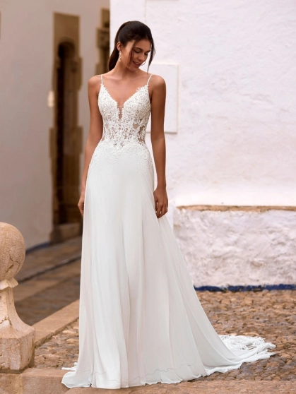 Love by Enzoani FLORETTA is an effortlessly romantic fit and flare wedding dress featuring a sheer illusion bodice adorned with intricate floral lace appliqués and delicate spaghetti straps. Soft illusion side panels create a flattering, sculpted silhouett