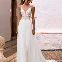 Love by Enzoani FLORETTA is an effortlessly romantic fit and flare wedding dress featuring a sheer illusion bodice adorned with intricate floral lace appliqués and delicate spaghetti straps. Soft illusion side panels create a flattering, sculpted silhouett