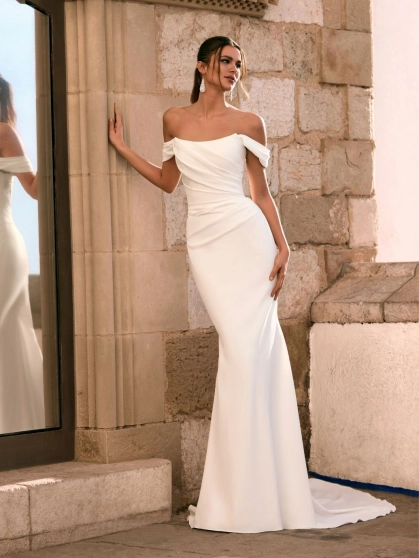 Love by Enzoani FRALISSE is a modern minimalist fit and flare wedding dress crafted with clean lines and timeless elegance. Featuring a softly draped off-the-shoulder neckline, flattering ruched bodice, sculpted silhouette and an open boned back bodice for
