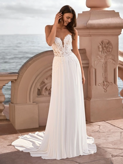 Love by Enzoani FRANCETTE is a romantic chiffon A-line wedding dress featuring an illusion lace corset bodice adorned with delicate floral lace appliqués, a plunging sweetheart neckline and a soft flowing chiffon skirt. Combining lightweight movement with
