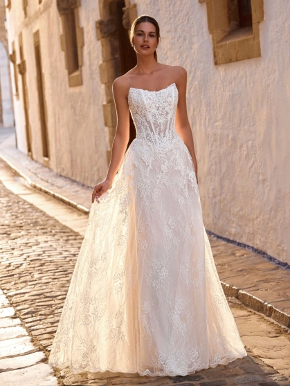 Love by Enzoani FRAVELLE is a romantic A-line wedding dress featuring a strapless sweetheart neckline, an illusion corset bodice with visible boning, intricate floral lace appliqués and a lightweight lace skirt with soft layers that create effortless movem