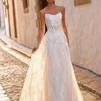 Love by Enzoani FRAVELLE is a romantic A-line wedding dress featuring a strapless sweetheart neckline, an illusion corset bodice with visible boning, intricate floral lace appliqués and a lightweight lace skirt with soft layers that create effortless movem