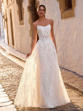 Love by Enzoani FRAVELLE is a romantic A-line wedding dress featuring a strapless sweetheart neckline, an illusion corset bodice with visible boning, intricate floral lace appliqués and a lightweight lace skirt with soft layers that create effortless movem