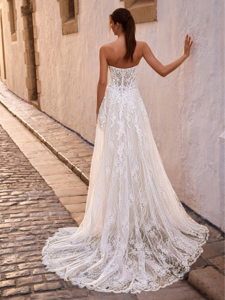 Love by Enzoani FRAVELLE is a romantic A-line wedding dress featuring a strapless sweetheart neckline, an illusion corset bodice with visible boning, intricate floral lace appliqués and a lightweight lace skirt with soft layers that create effortless movem