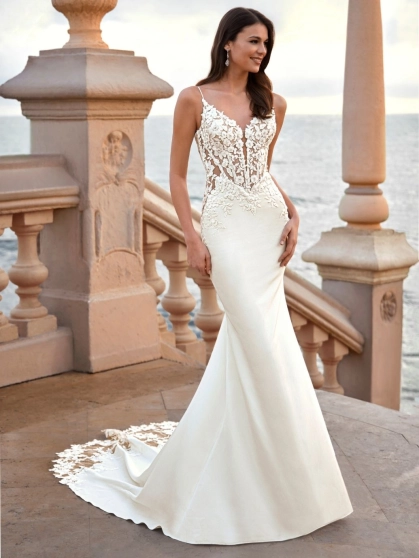Love by Enzoani FRELYNN is a sophisticated fitted wedding dress featuring delicate spaghetti straps, an illusion corset bodice adorned with dimensional floral lace appliqués and exposed boning, paired with a sleek crepe mermaid skirt. The figure-enhancing